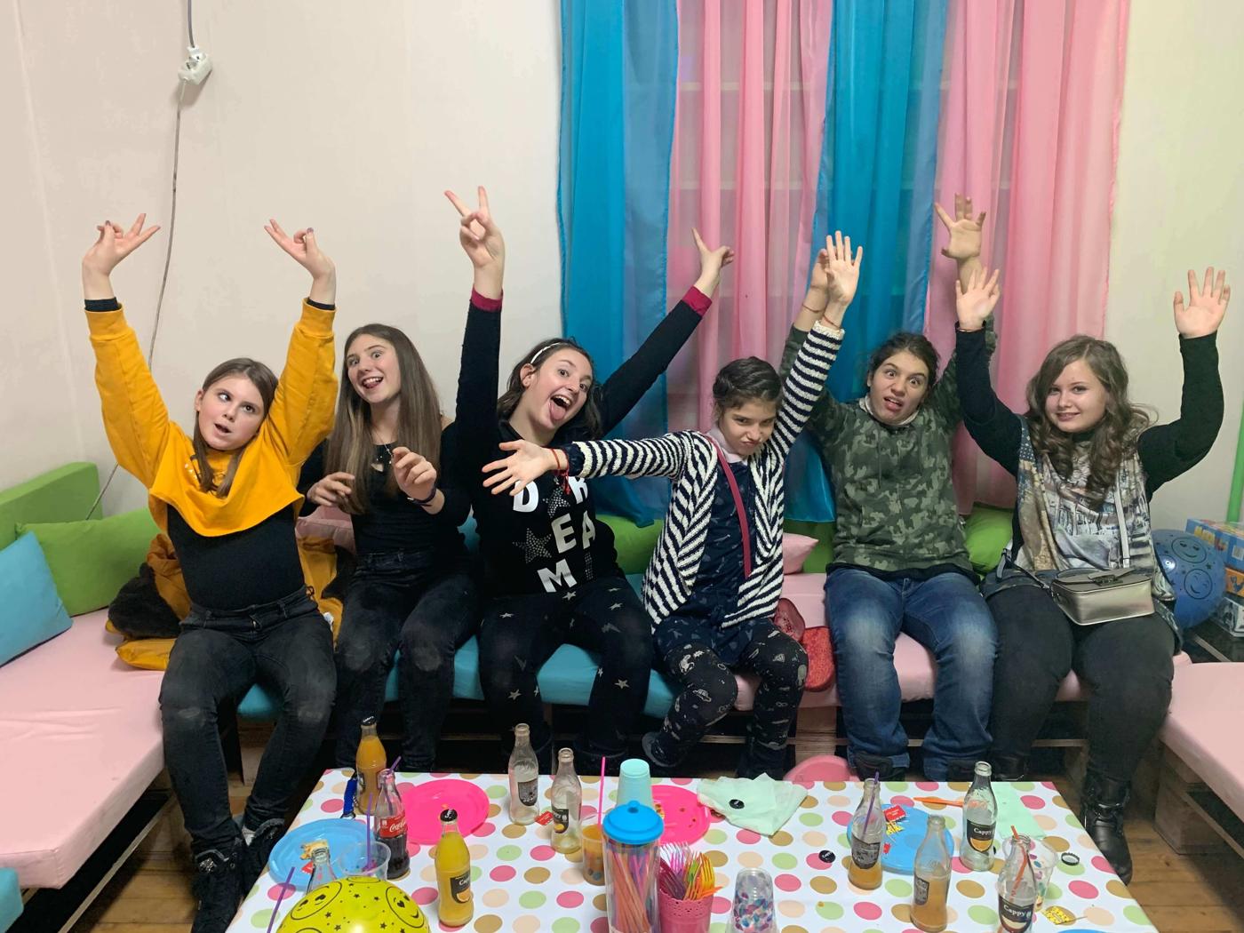 Деца с ръце във въздуха около масата в парти залата